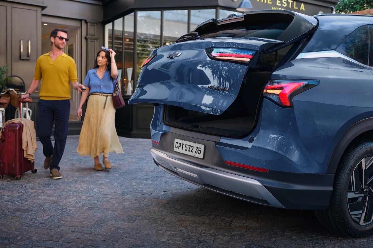 Imagen de un hombre y una mujer saliendo de un hotel a punto de cargar sus valijas en el baúl de la Chevrolet Captiva PHEV.
