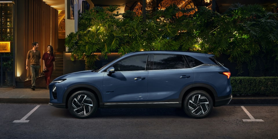 Vista lateral de la Chevrolet Captiva PHEV estacionada en la puerta de un restaurante, mientras un hombre y una mujer salen por la puerta del local.