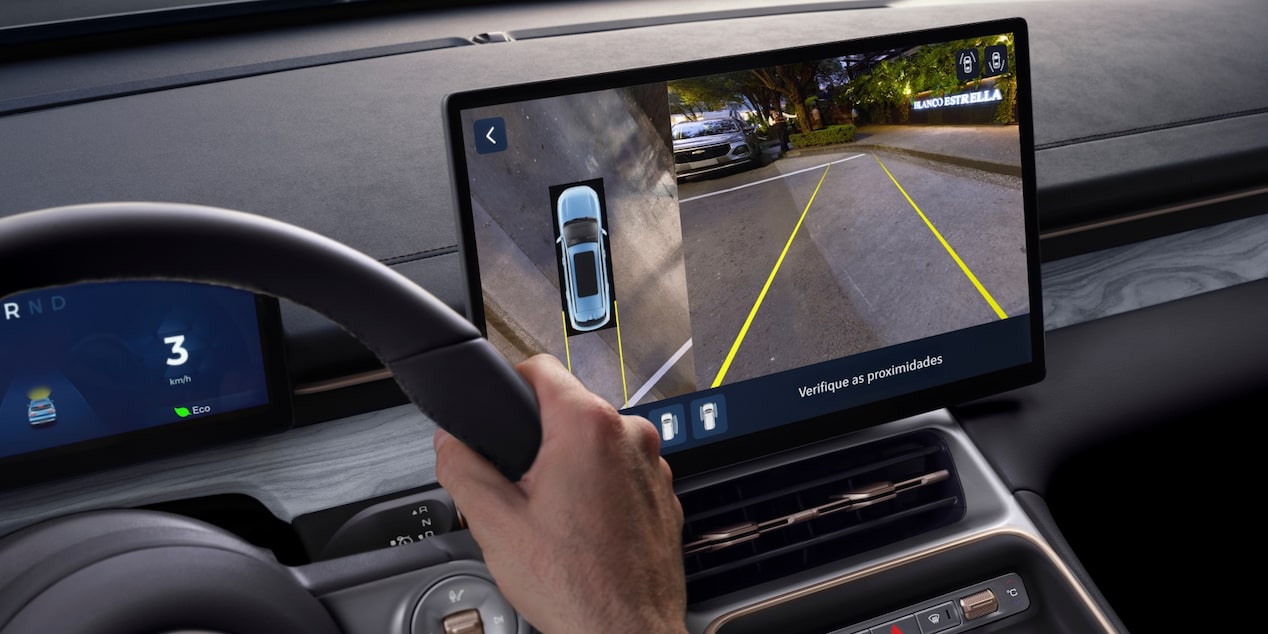 Imagen desde el punto de vista del conductor mientras observa la pantalla central digital y estaciona con la asistencia de la cámara trasera.