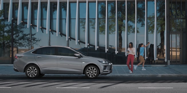 Chevrolet Onix Plus estacionado con personas cerca.