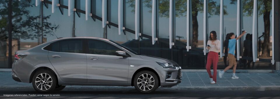 Chevrolet Onix Plus estacionado con personas caminando cerca.