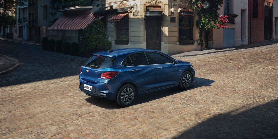 Vista traseira do Onix Azul Boreal em rua com arquitetura clássica.