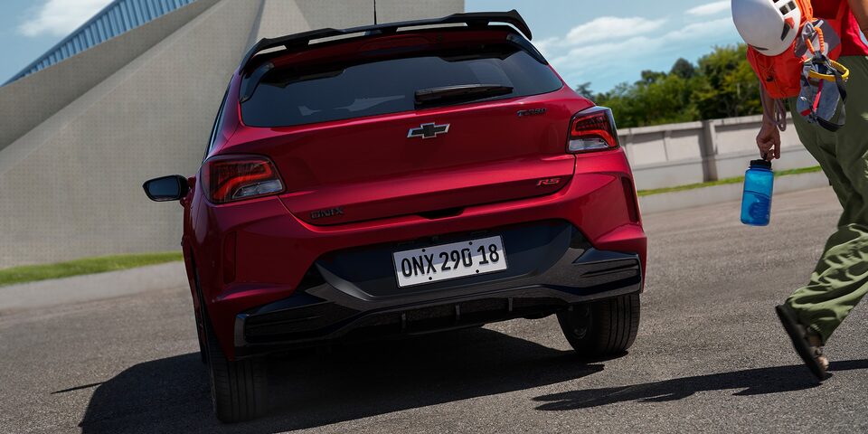 Traseira do Chevrolet Onix RS com lanternas acesas.