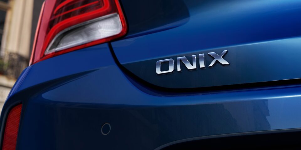 Chevrolet Onix Azul Boreal com detalhe em prata escrito Onix e lanterna traseira.