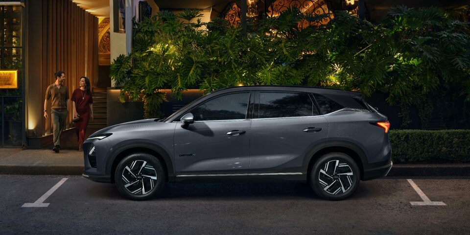 Captiva EV cinza estacionado em frente a um restaurante iluminado, com um casal saindo do local à noite.
