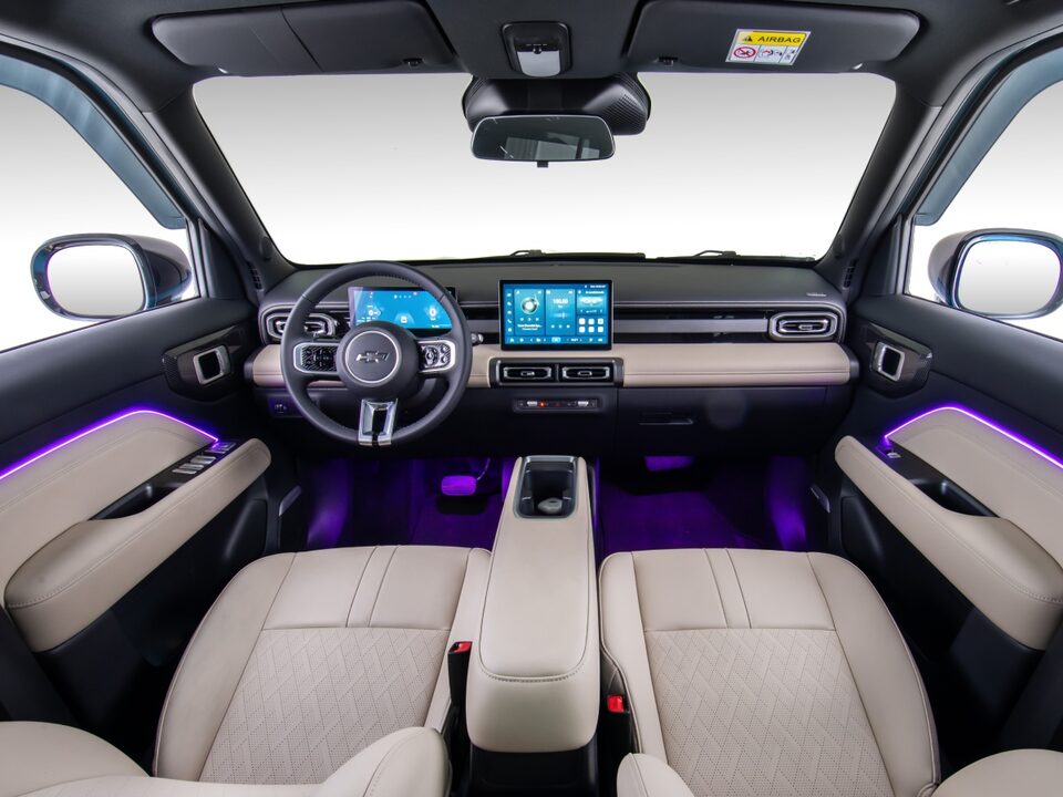 Interior do Chevrolet Spark EUV com bancos em acabamento claro, central multimídia acesa e iluminação interna em LED RGB na cor roxa nas portas e assoalho.