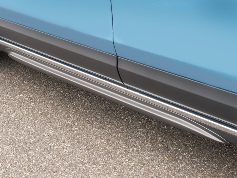 Detalhe das saias laterais instaladas no Chevrolet Spark EUV, com acabamento metálico sobre piso asfaltado.