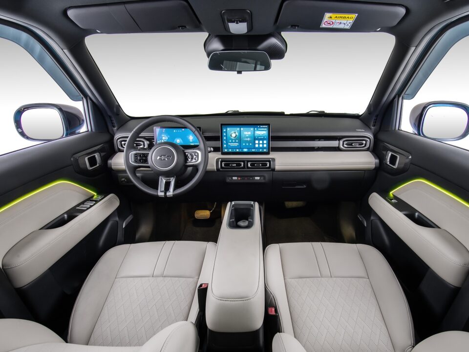 Interior do Chevrolet Spark EUV com bancos em acabamento claro, central multimídia acesa e iluminação interna em LED RGB na cor amarela nas portas e assoalho.