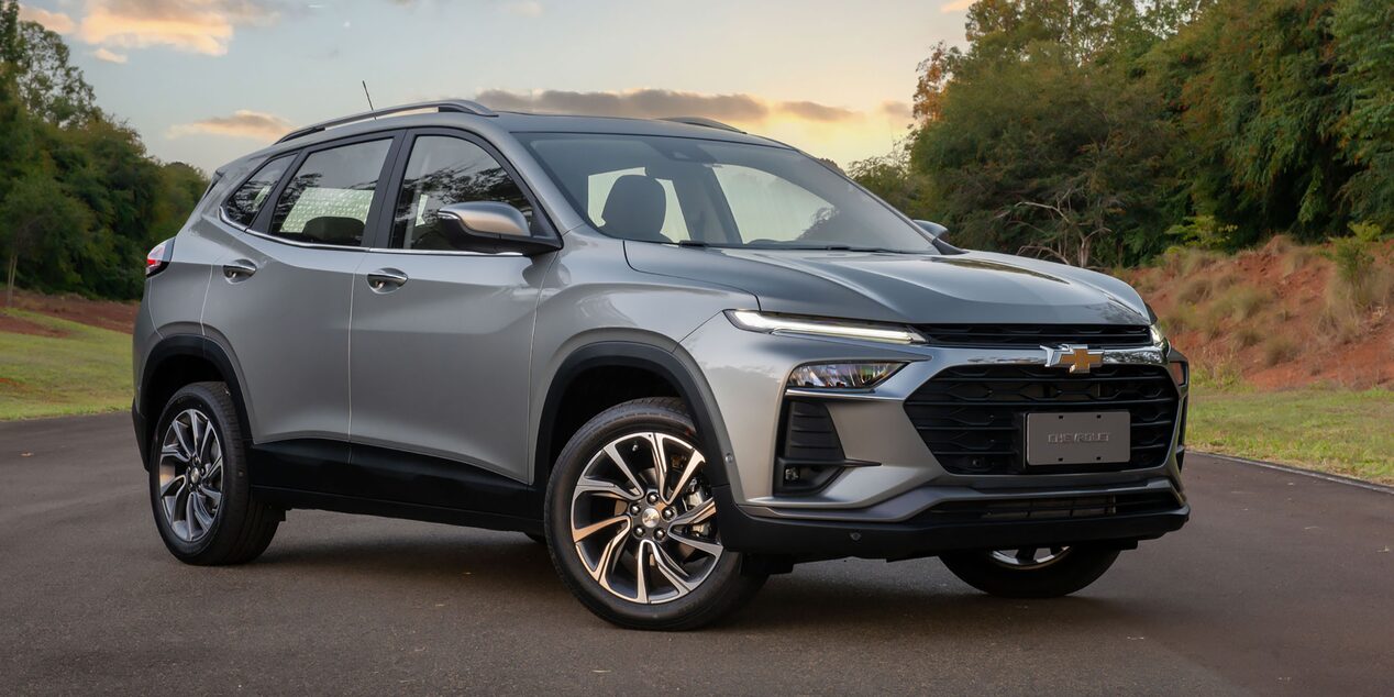 Chevrolet Tracker visto de frente e lateral direita, estacionado em pista aberta com vegetação ao fundo.