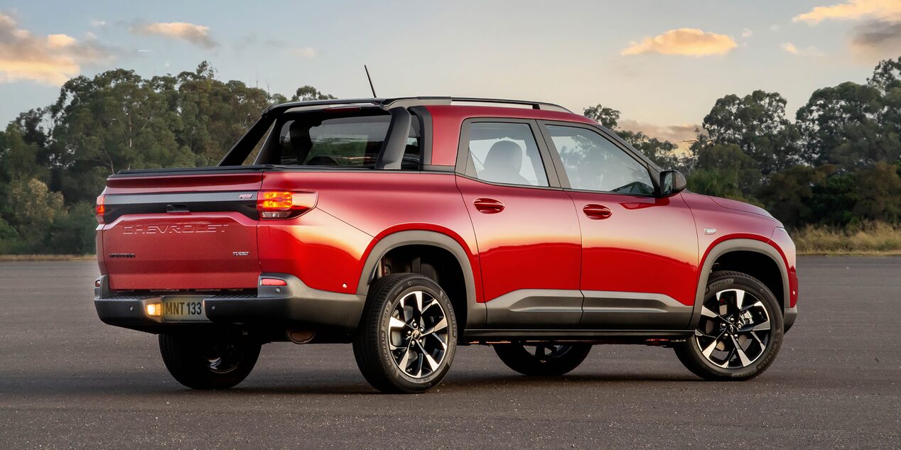 Chevrolet Montana vista de traseira e lateral esquerda, estacionada em pista aberta ao pôr do sol.