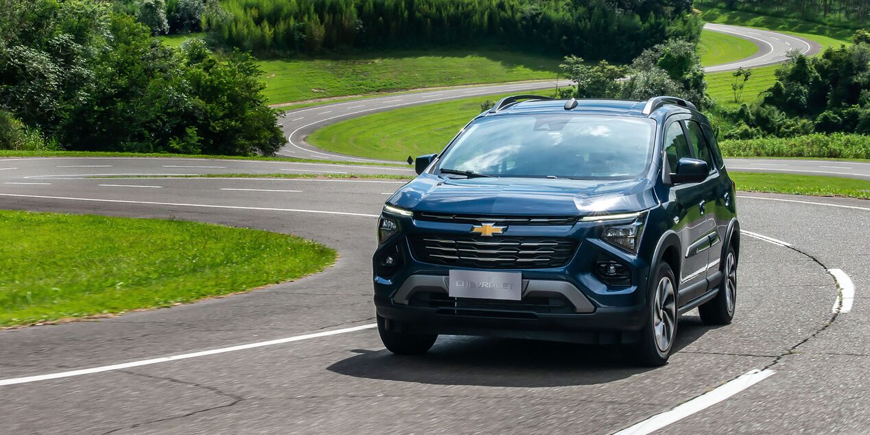 Chevrolet Spin visto de frente, em movimento em pista curva cercada por área verde.