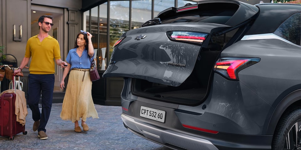 Una pareja acercandose a la Chevrolet Captiva EV para guardar sus pertenencias en el maletero.