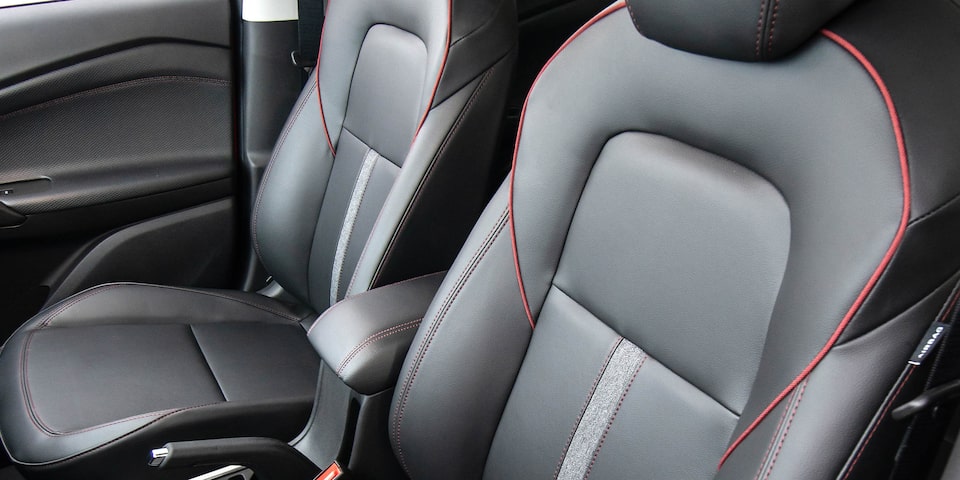 Interior de la Chevrolet Tracker 2025 con asientos de cuero, costuras rojas y diseño ergonómico para máximo confort