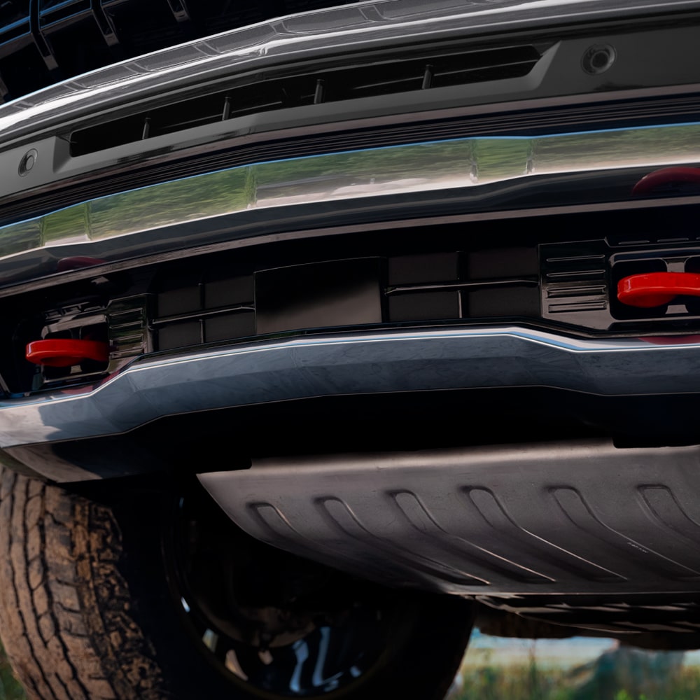 Vista en primer plano de la parte trasera inferior de una Chevrolet Tahoe, mostrando el paragolpes, la protección metálica inferior y detalles del chasis.