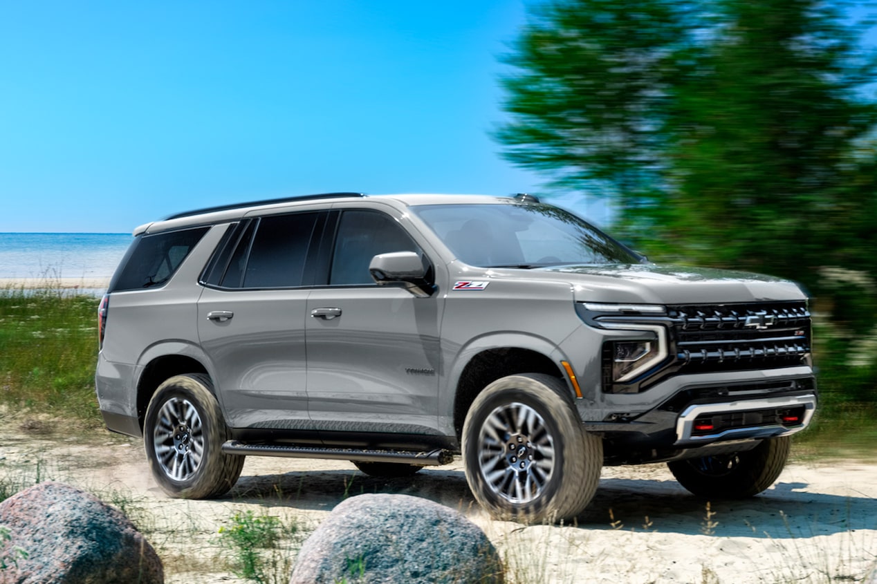 Chevrolet Tahoe andando sobre un camino de arena, con árboles y el mar de fondo.