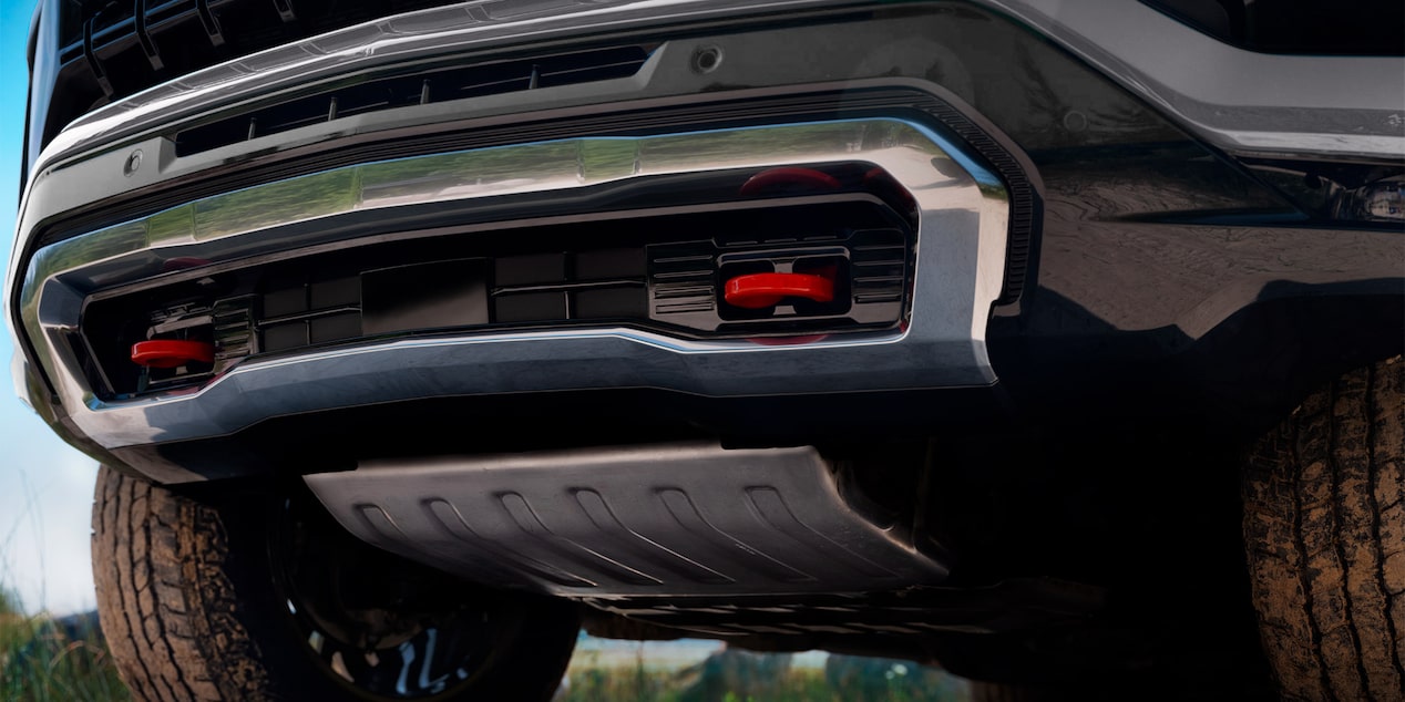 Vista en primer plano de la parte trasera inferior de una Chevrolet Tahoe, mostrando el paragolpes, la protección metálica inferior y detalles del chasis.