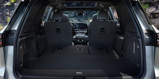 Primer plano del panel de controles del interior de una Chevrolet Tahoe, con botones de asistencia a la conducción, freno de estacionamiento, climatización automática y perillas de ajuste.