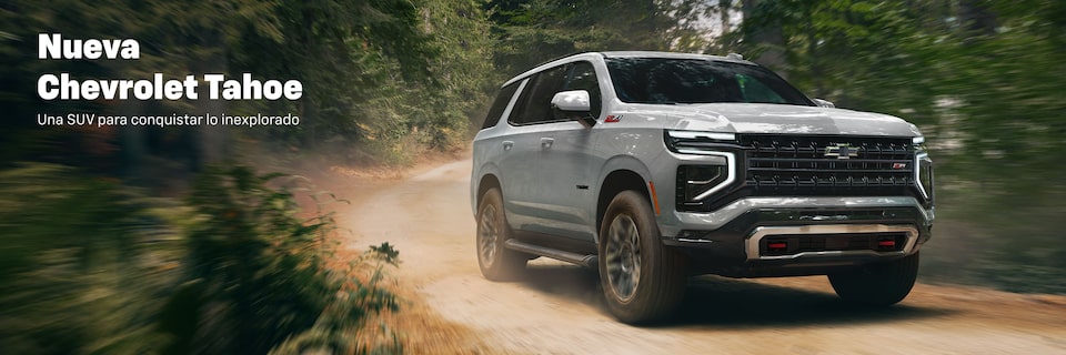 Nueva Chevrolet Tahoe conduciendo por camino de tierra en el bosque, diseñada para conquistar lo inexplorado
