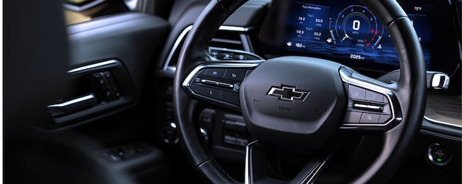 Interior de Chevrolet Tahoe mostrando el volante con emblema Chevrolet y panel digital iluminado
