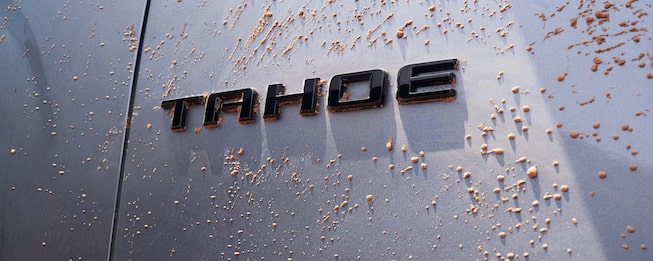 Close-up del emblema Chevrolet Tahoe cubierto de barro, representando resistencia, aventura y espíritu off-road del SUV