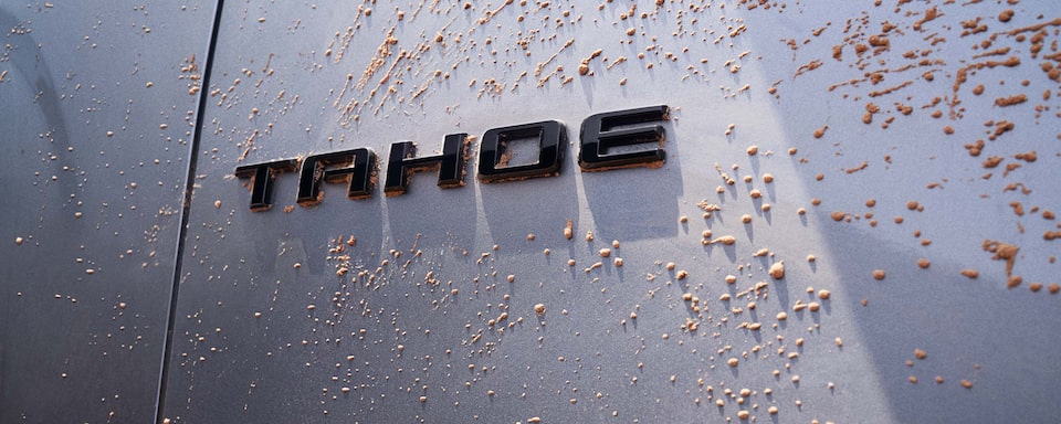 Detalle del logo Chevrolet Tahoe cubierto de barro, representando su resistencia en condiciones todoterreno