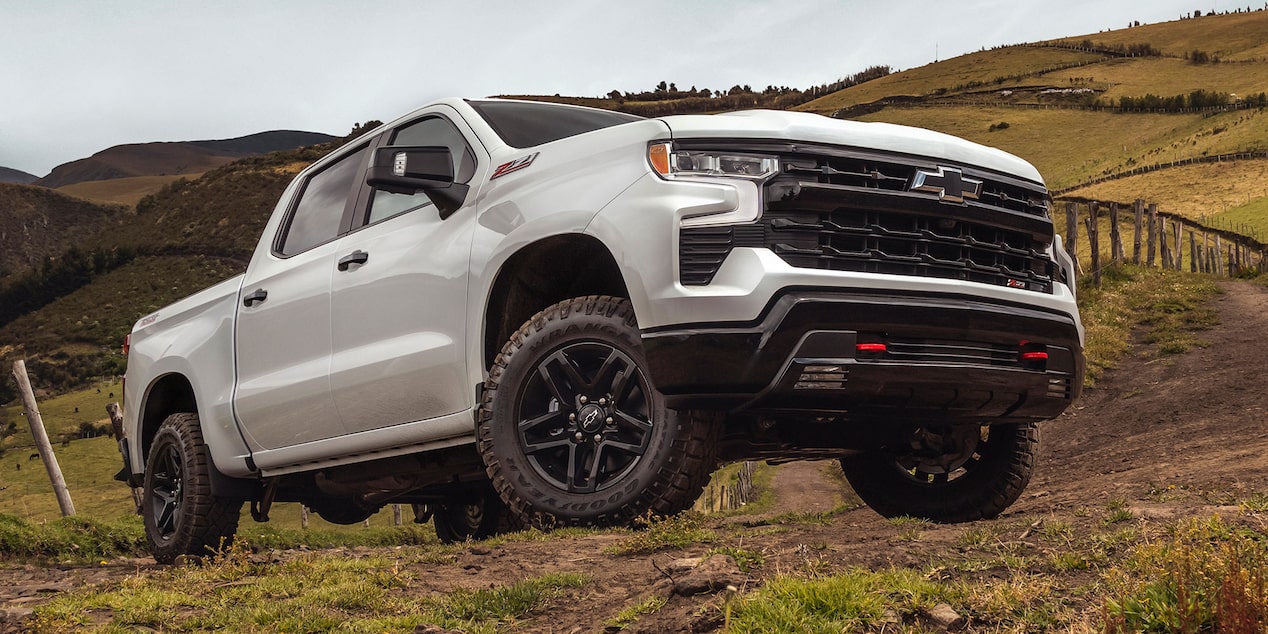 Imagen de una Chevrolet Silverado subiendo por un camino de tierra delimitado por un alambrado, on caballos y naturaleza de fondo.