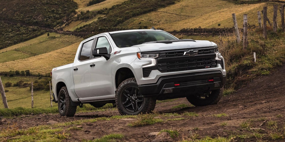 Imagen de una Chevrolet Silverado subiendo por un camino de tierra delimitado por un alambrado, con caballos y naturaleza de fondo.