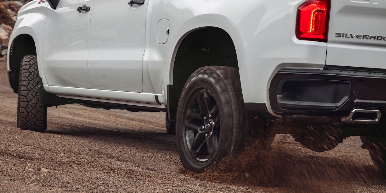 Vista trasera de una Chevrolet Silverado andando sobre camino de ripio.