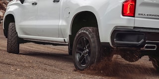 Vista trasera de una Chevrolet Silverado andando sobre camino de ripio.