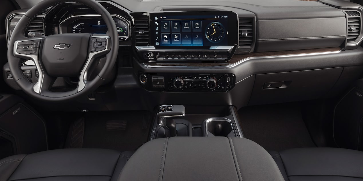 Vista interior de la Chevrolet Silverado, mostrando volante, pantalla digital táctil, controles del aire acondicionado, guantera y más.