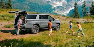 Chevrolet Suburban con una familia jugando alrededor.