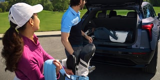Imagen de un hombre y una mujer cargando equipos de golf en el baúl de la Chevrolet Blazer EV.