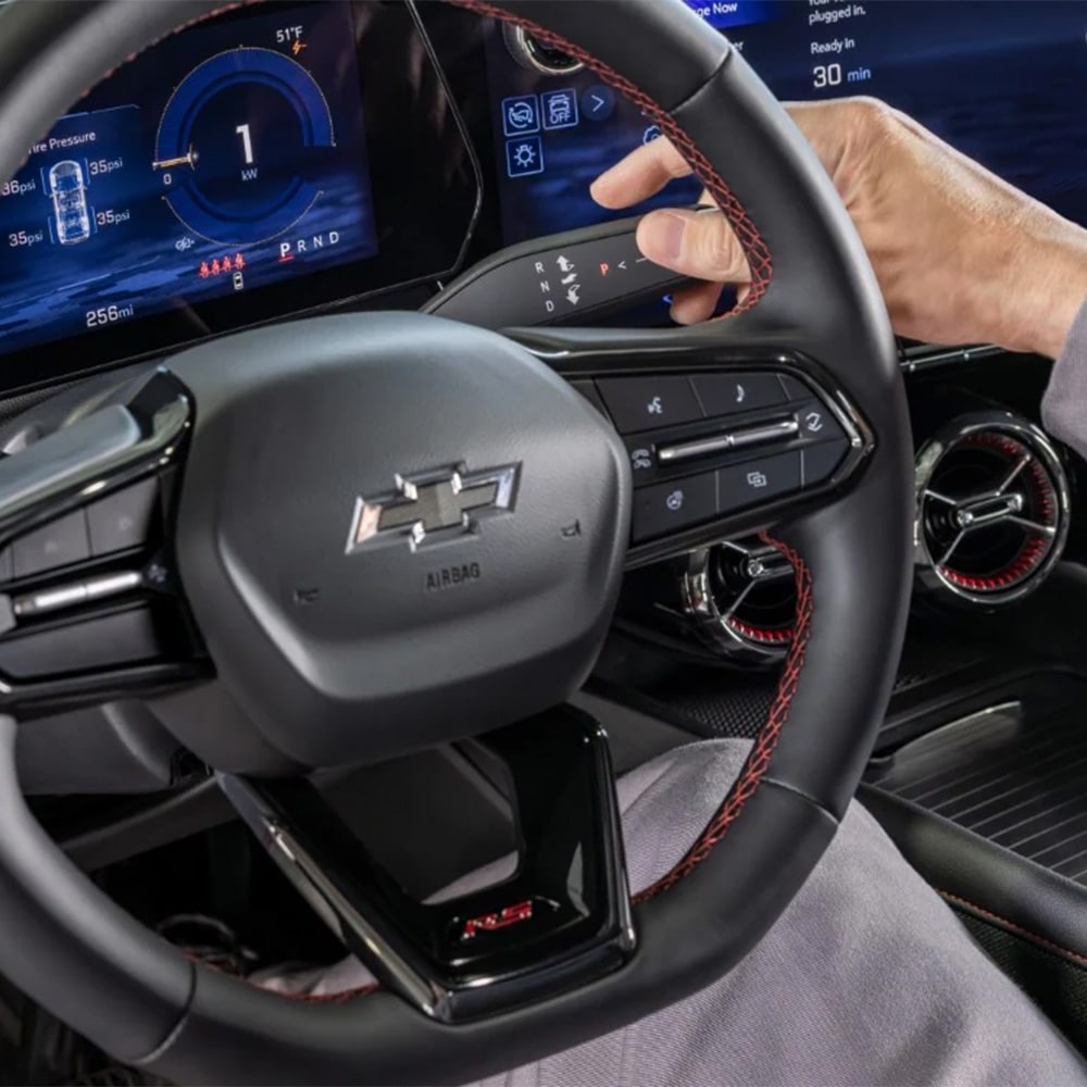 Imagen en detalle del volante de la Chevrolet Blazer EV, mientras la mano del conductor activa uno de sus botones.