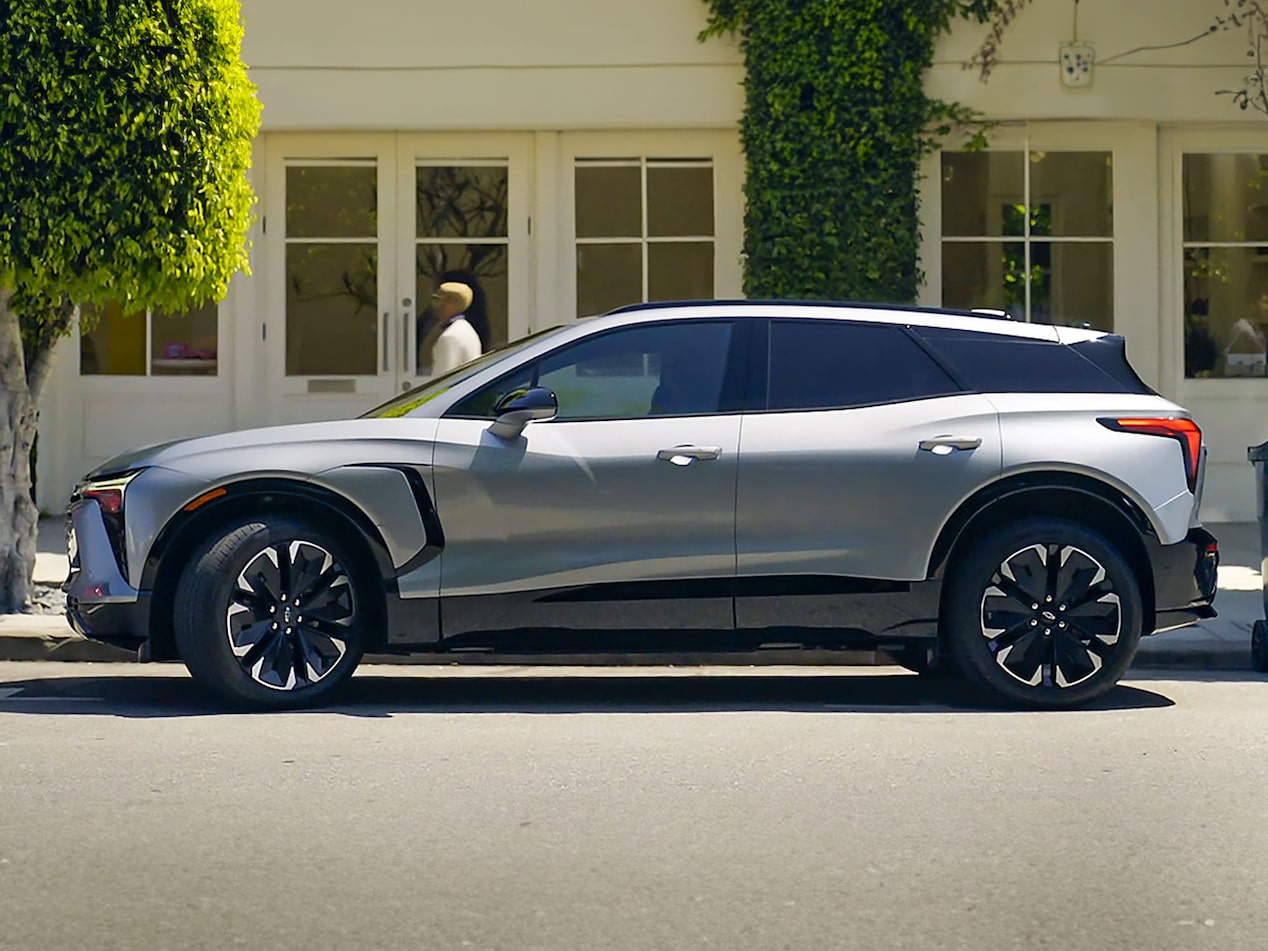 Chevrolet Blazer EV estacionada en la puerta de una casa, mientras una persona pasa caminando a su lado.