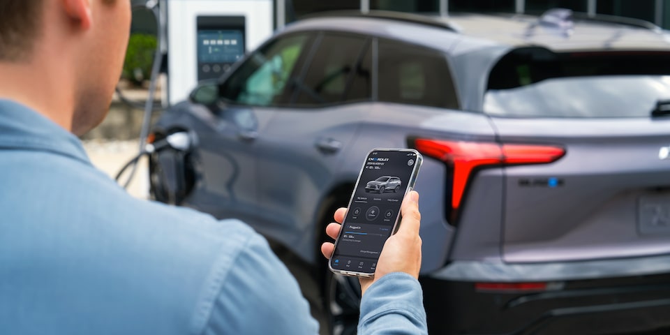 Imagen de un hombre utilizando la app myChevrolet mientras se carga su Blazer EV.